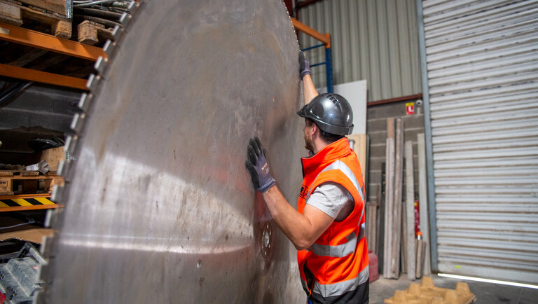 Un collaborateur manipule une grande scie circulaire